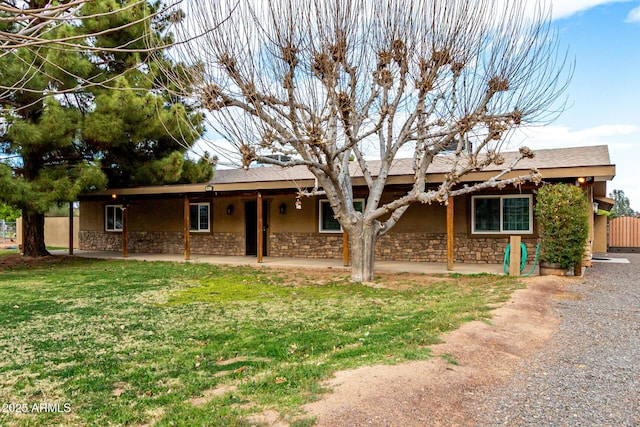 ranch-style home with stucco siding, stone siding, a patio, and a front lawn