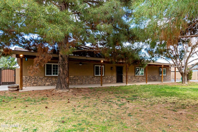 view of front of property with stone siding, stucco siding, a patio, and a gate