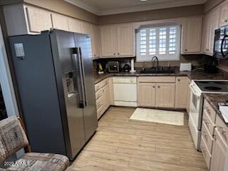 kitchen with light wood-type flooring, white appliances, and sink