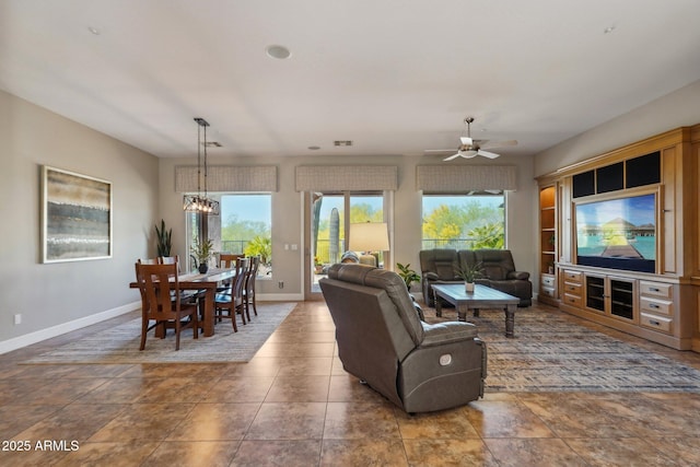 living area with visible vents, baseboards, and ceiling fan with notable chandelier