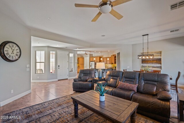 tiled living area featuring baseboards, a ceiling fan, and visible vents