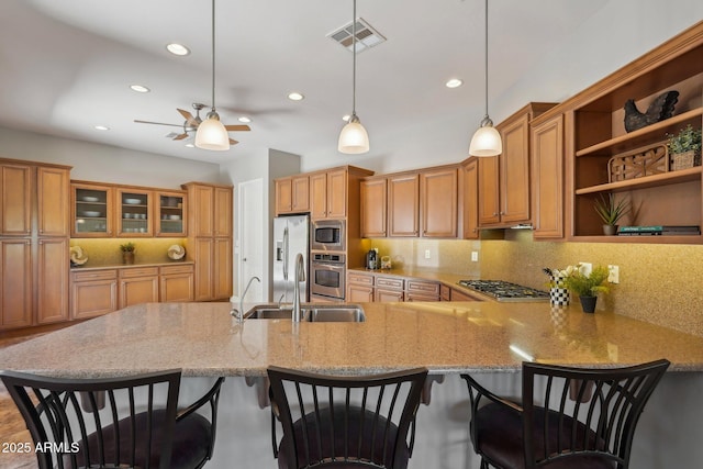 kitchen with recessed lighting, a peninsula, visible vents, brown cabinetry, and stainless steel appliances