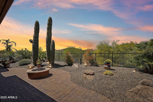 patio terrace at dusk featuring a fire pit and fence