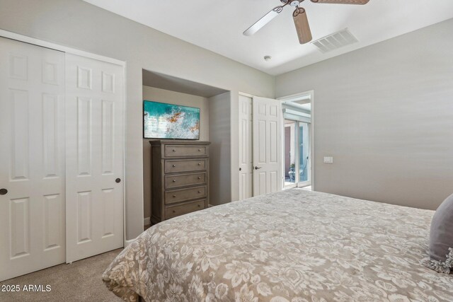 bedroom with visible vents, multiple closets, a ceiling fan, and carpet flooring