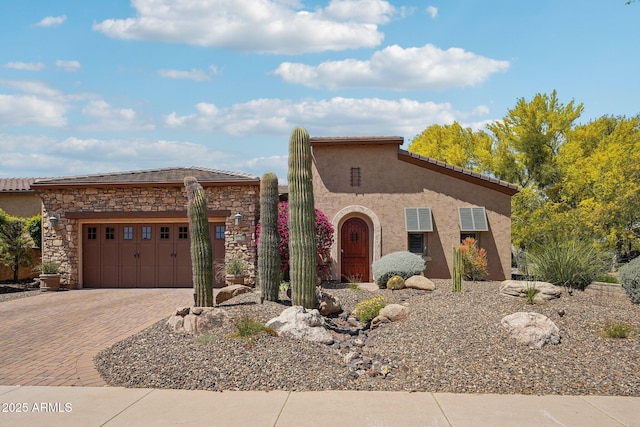 mediterranean / spanish-style house featuring a garage, stucco siding, a tile roof, and decorative driveway
