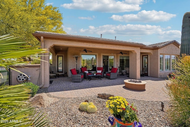 back of house featuring a patio, stucco siding, a ceiling fan, an outdoor living space with a fire pit, and a tile roof