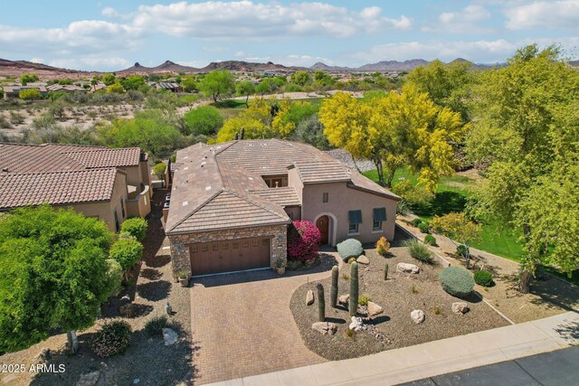 view of front of home featuring stone siding, a garage, a tile roof, stucco siding, and driveway