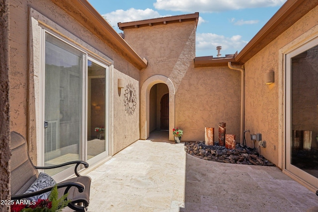 view of exterior entry with a patio and stucco siding