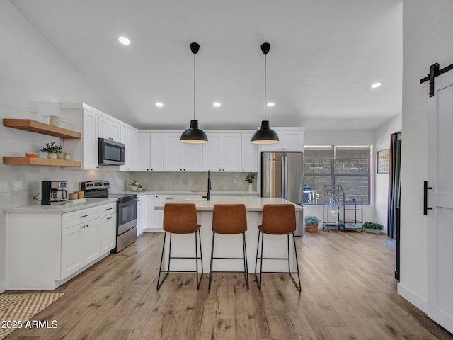 12641 S 39th Pl, Phoenix, AZ 85044 - kitchen featuring stainless steel appliances, a barn door, tasteful backsplash, white cabinetry, and a kitchen bar
