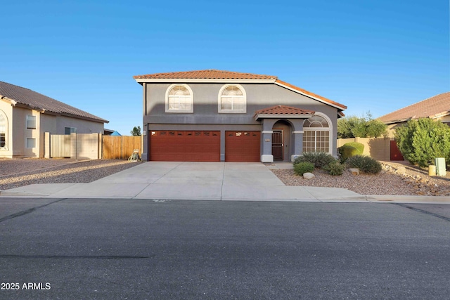 mediterranean / spanish-style house with fence, driveway, an attached garage, stucco siding, and a tile roof