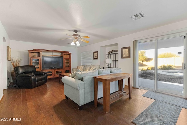 living room featuring dark wood finished floors, visible vents, arched walkways, and ceiling fan