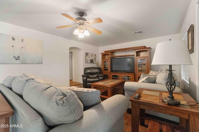 living room featuring visible vents, arched walkways, wood finished floors, and a ceiling fan