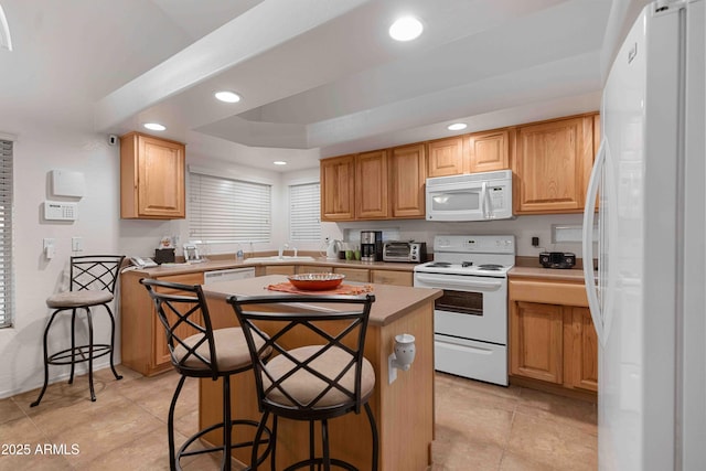 kitchen with white appliances, recessed lighting, a raised ceiling, and a kitchen island