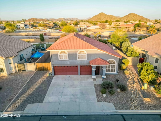 view of front of house featuring fence, concrete driveway, a garage, a tiled roof, and a mountain view