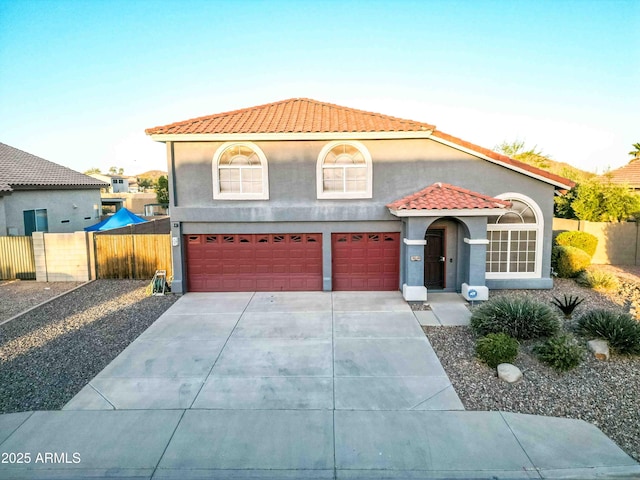 mediterranean / spanish-style house featuring a tile roof, fence, and stucco siding