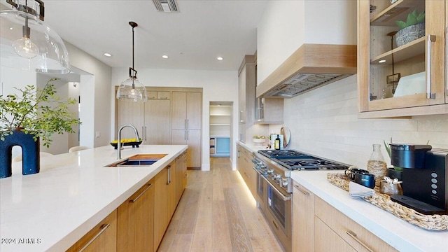 kitchen with light brown cabinets, sink, hanging light fixtures, light hardwood / wood-style flooring, and premium range hood