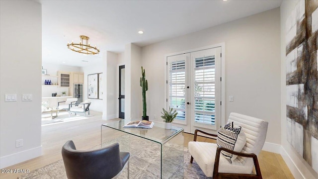 sitting room featuring french doors, a chandelier, and light wood-type flooring