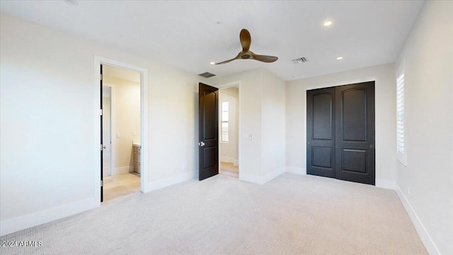 unfurnished bedroom with light carpet, a closet, ensuite bath, and ceiling fan