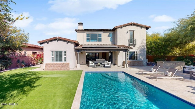 back of property with an outdoor living space, a patio, and a lawn