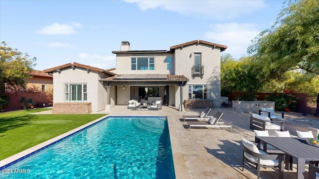 rear view of property featuring an outdoor living space, a fenced in pool, a balcony, a yard, and a patio area