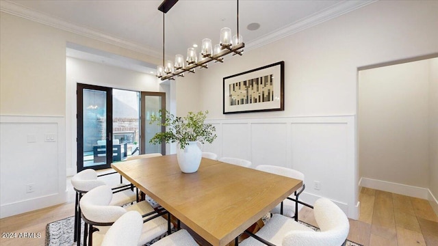 dining room with a notable chandelier, crown molding, and light hardwood / wood-style flooring