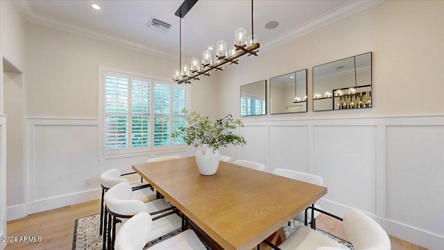 dining space featuring an inviting chandelier, ornamental molding, and light wood-type flooring