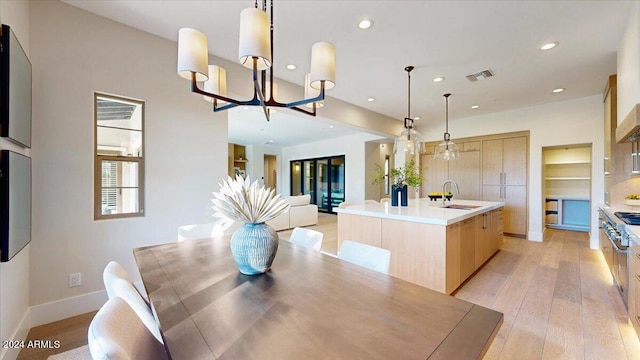 dining space featuring light hardwood / wood-style flooring, a notable chandelier, and sink