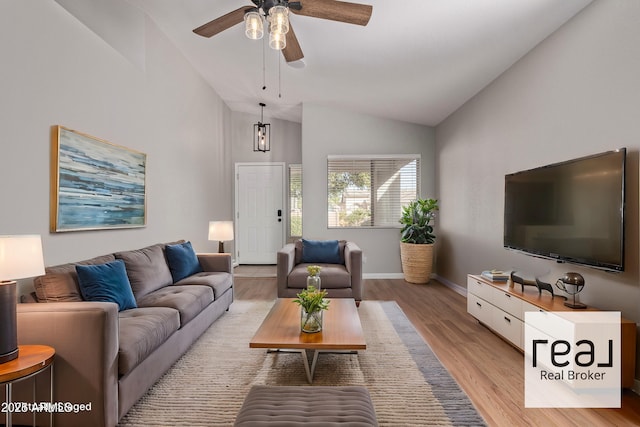 living room with ceiling fan, light wood-type flooring, and vaulted ceiling