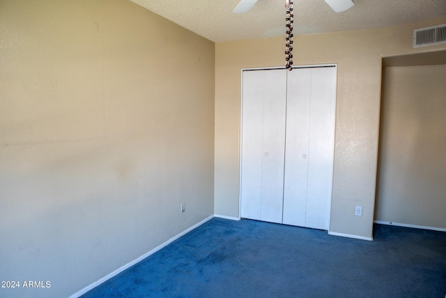 unfurnished bedroom with ceiling fan, a closet, a textured ceiling, and dark colored carpet