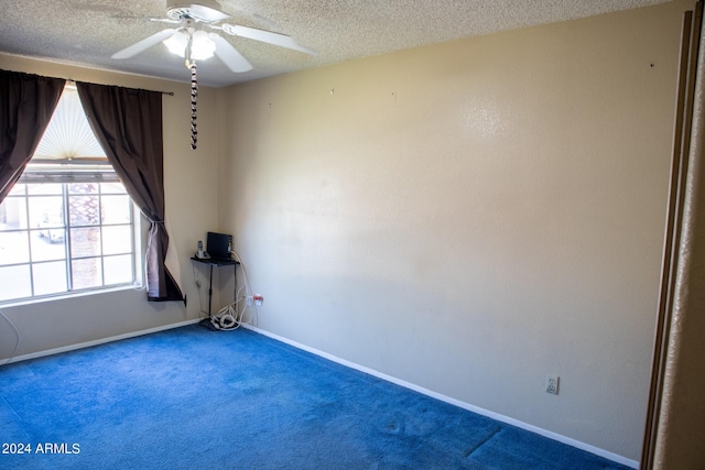 carpeted empty room featuring ceiling fan and a textured ceiling