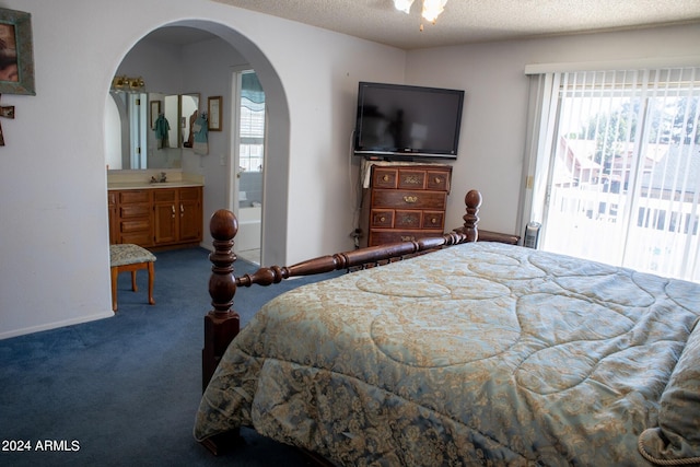 carpeted bedroom with access to exterior, a textured ceiling, ensuite bathroom, and sink