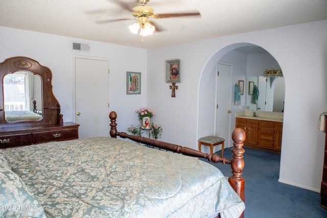 bedroom featuring dark colored carpet, ceiling fan, a textured ceiling, and connected bathroom