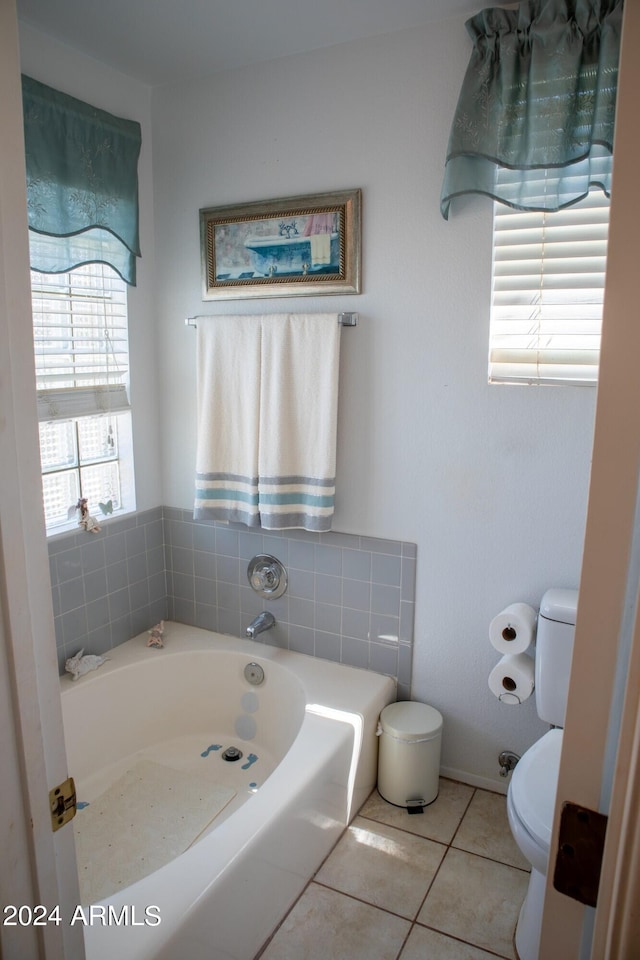 bathroom featuring tile patterned flooring, a bath, and toilet