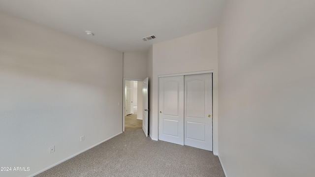 unfurnished bedroom with light carpet and a closet