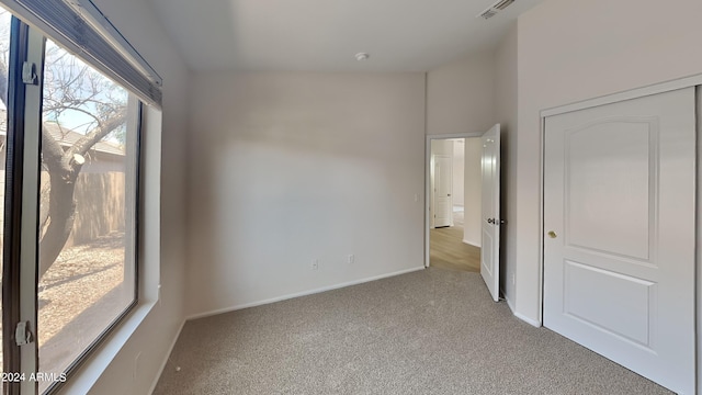 unfurnished bedroom with light carpet, a closet, and vaulted ceiling