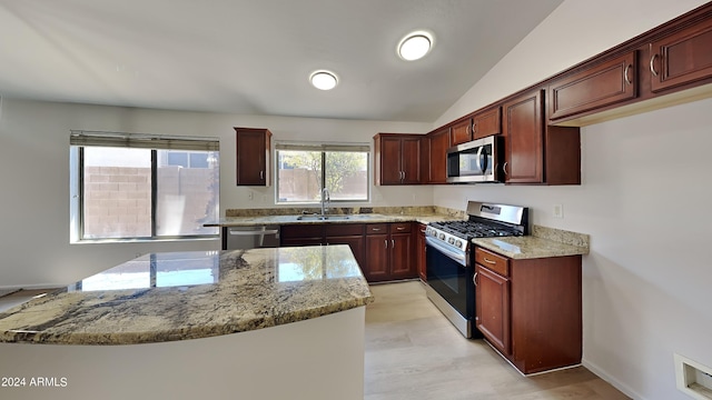 kitchen featuring light stone counters, vaulted ceiling, stainless steel appliances, and sink