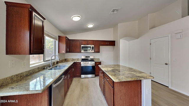 kitchen featuring light stone counters, a kitchen island, stainless steel appliances, lofted ceiling, and sink