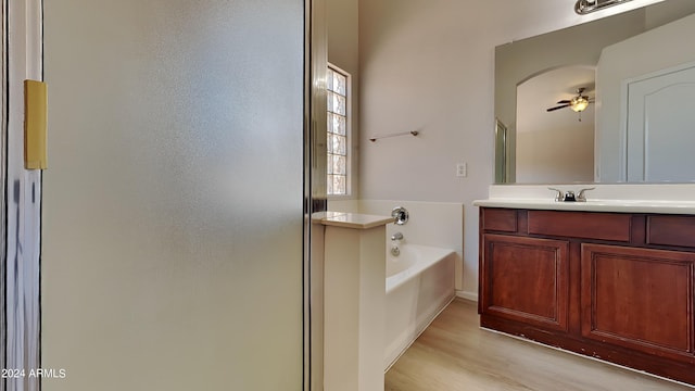 bathroom with shower with separate bathtub, vanity, hardwood / wood-style floors, and ceiling fan