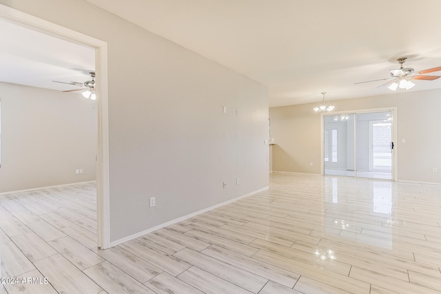 unfurnished room with ceiling fan with notable chandelier and light hardwood / wood-style flooring