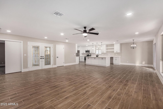 unfurnished living room with french doors and ceiling fan with notable chandelier