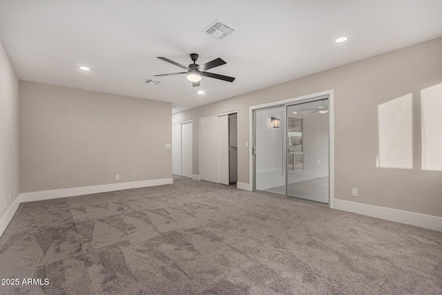 unfurnished bedroom with carpet flooring, ceiling fan, and multiple closets