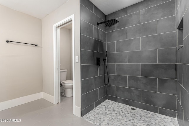 bathroom featuring tile patterned floors, toilet, and tiled shower