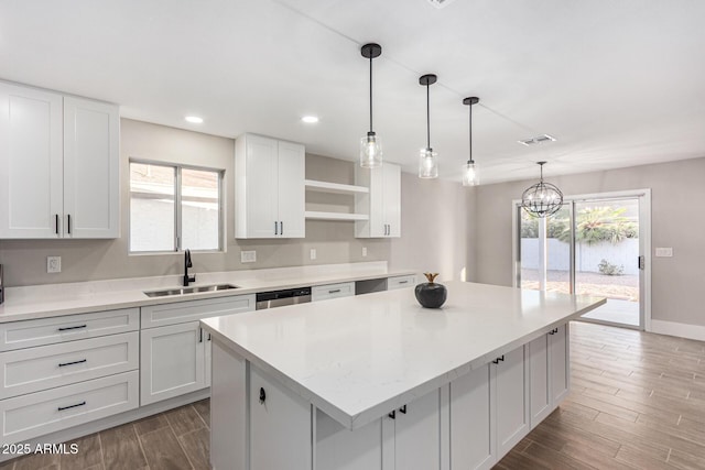 kitchen featuring pendant lighting, a center island, sink, white cabinetry, and a chandelier