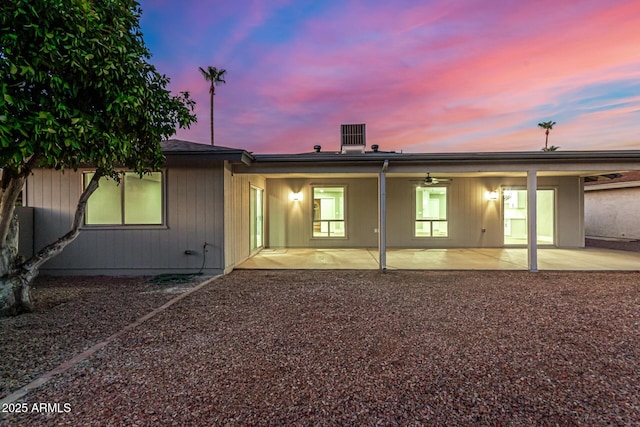 back house at dusk featuring a patio