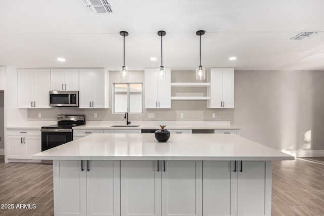 kitchen featuring white cabinets, appliances with stainless steel finishes, light wood-type flooring, and a kitchen island