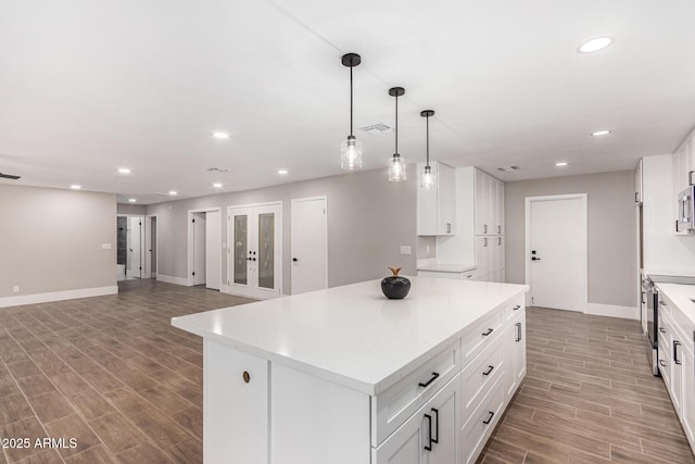 kitchen featuring white cabinets, french doors, a kitchen island, and hanging light fixtures