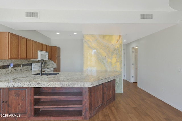 kitchen featuring white appliances, wood-type flooring, kitchen peninsula, and sink