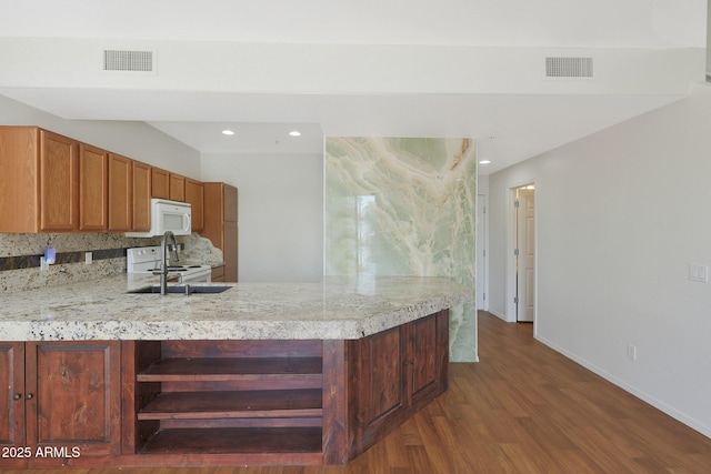 kitchen with white appliances, dark wood-type flooring, sink, tasteful backsplash, and kitchen peninsula