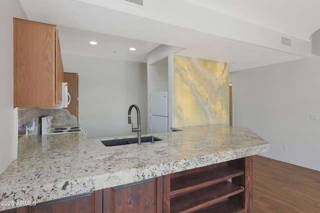 kitchen with kitchen peninsula, dark wood-type flooring, sink, white refrigerator, and range