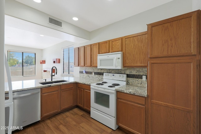 kitchen featuring light stone countertops, sink, dark hardwood / wood-style flooring, white appliances, and decorative backsplash